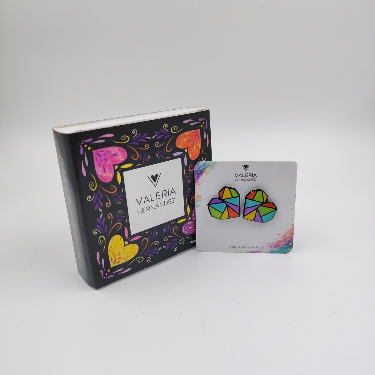 “Aros geométricos multicolor de resina pintados a mano, junto a packaging ilustrado de Valeria Hernández.”